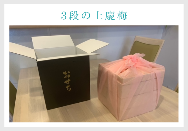 2022オイシックスのおせちレビュー。黒い外箱からを取り出すと、上梅慶がピンクの風呂敷に包まれている